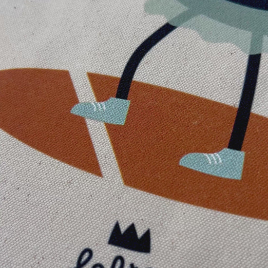 Tote bag « Jeu, set et lune » de Lolilé, représentant un petit personnage noir en tenue de tennis tenant une raquette et jouant avec une grande lune sur fond quadrillé bleu clair.
