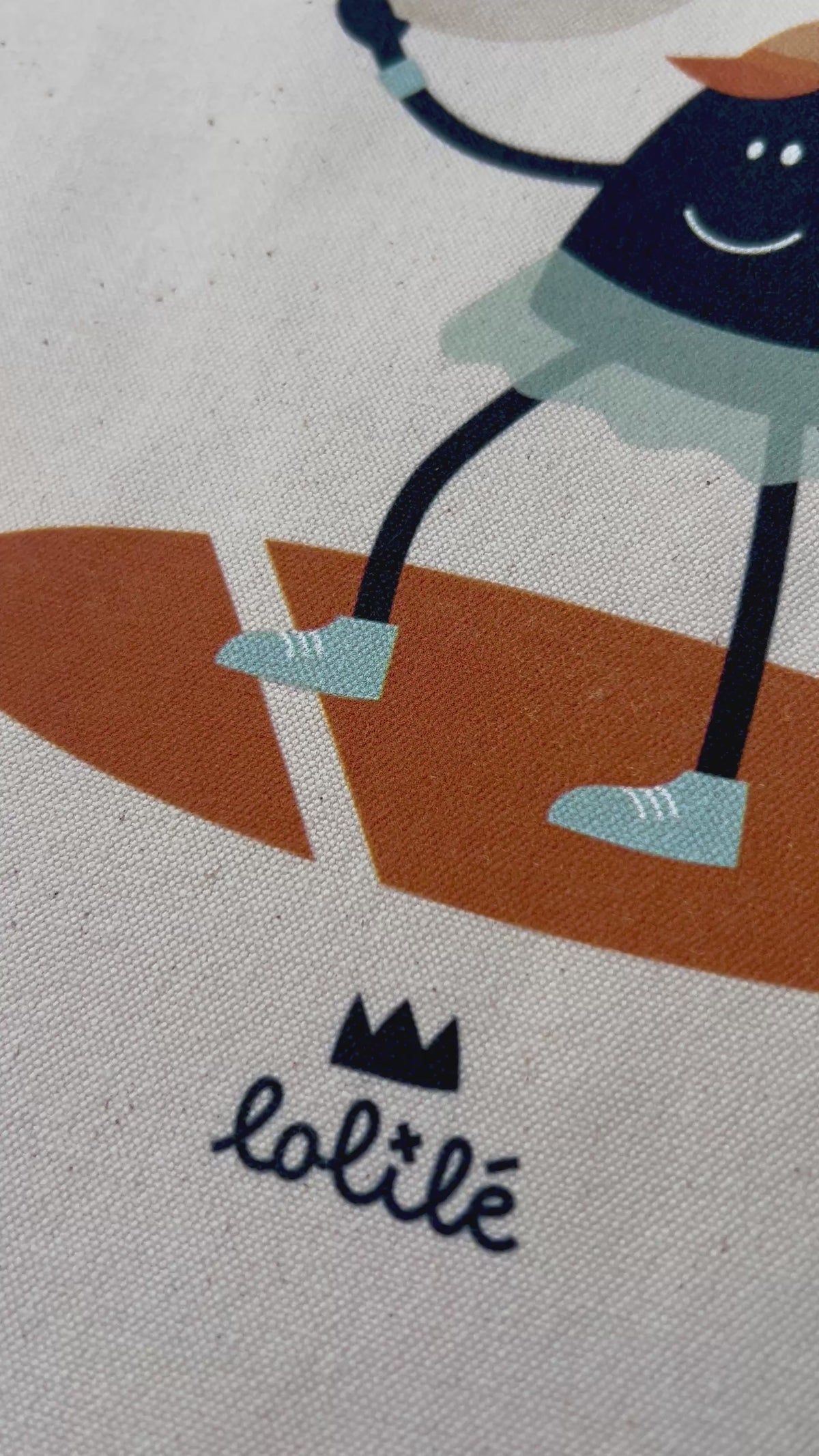 Tote bag « Jeu, set et lune » de Lolilé, représentant un petit personnage noir en tenue de tennis tenant une raquette et jouant avec une grande lune sur fond quadrillé bleu clair.